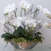 Lifelike orchids in a mirrored boat vase